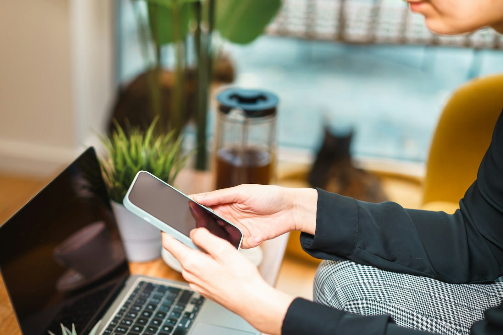 Person using smartphone while working on laptop digital minimalism guide