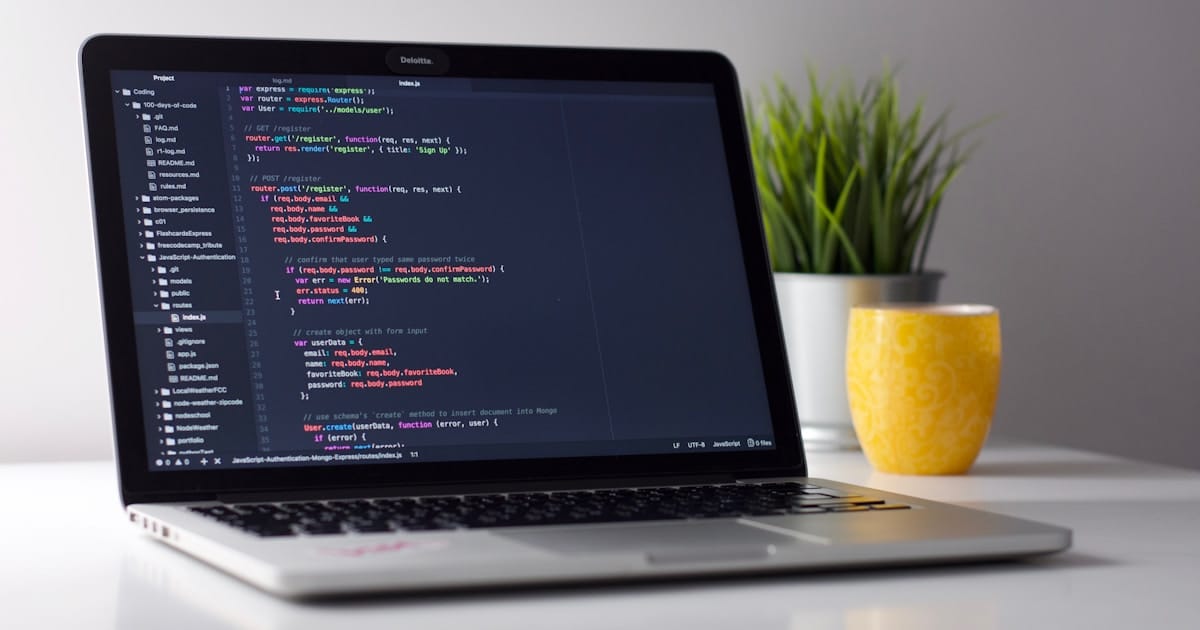 Laptop screen showing code and creative work on a wooden desk